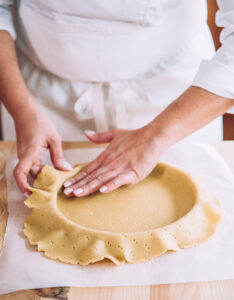 foncage traditionnel d'une pâte sucrée dans un cercle à pâtisserie